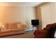 Living room with beige sofa, patterned armchair, a television, and light carpet at 670 Avenue N Se, Winter Haven, FL 33880