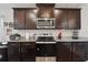 Modern kitchen with stainless steel appliances, granite countertops, and dark wood cabinetry at 730 Colville Pl, Kissimmee, FL 34759