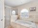 Elegant bathroom featuring a soaking tub with decorative window and separate glass-enclosed shower at 780 Gila Dr, Kissimmee, FL 34759
