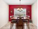 Bright dining room with bold red wall, large window, and modern chandelier at 780 Gila Dr, Kissimmee, FL 34759