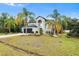 Landscaped exterior view of home showing the 2-car garage, palms, grass, and blue sky at 780 Gila Dr, Kissimmee, FL 34759