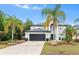 Two story home featuring a grey exterior, dark garage door, and landscaping with palm trees at 780 Gila Dr, Kissimmee, FL 34759
