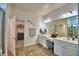This bathroom features double sinks, vanity space, wood-look tile flooring, and a walk-in closet at 825 Grazie Loop, Davenport, FL 33837