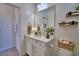 Well-lit bathroom with modern fixtures, featuring a white vanity, mirror, and practical open shelving at 825 Grazie Loop, Davenport, FL 33837