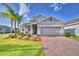 Charming home with a brick driveway, two-car garage, and beautifully landscaped front yard at 825 Grazie Loop, Davenport, FL 33837