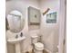 Clean and modern powder room with pedestal sink, decorative mirror, and beach-themed decor at 825 Grazie Loop, Davenport, FL 33837