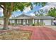 Charming single-story home with red brick driveway and lush green tree in the front yard at 842 Cinnamon Dr, Winter Haven, FL 33880