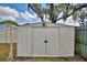Exterior view of a white storage shed in the backyard with a double-door entry and overhead lighting fixture at 842 Cinnamon Dr, Winter Haven, FL 33880