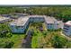 An aerial view showcases the property's architecture, surrounding greenery, and tranquil pond at 100 El Camino Dr # 309, Winter Haven, FL 33884