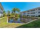 Back of the condo building overlooking a small lake, bridge, and landscaping at 100 El Camino Dr # 309, Winter Haven, FL 33884