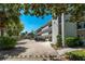 White condo building with balconies, lush trees, and parking area at 100 El Camino Dr # 309, Winter Haven, FL 33884