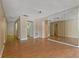 Living room with wood floors leading to the kitchen featuring white cabinets and appliances, plus access to the front door at 100 El Camino Dr # 309, Winter Haven, FL 33884