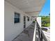 Exterior walkway of condo building with black metal railings, white walls, and a view of the surrounding trees at 100 El Camino Dr # 309, Winter Haven, FL 33884