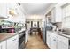 View of the white kitchen that opens to a dining room with stainless steel appliances and wood flooring at 100 Ellen Ct, Winter Haven, FL 33884