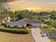 Charming single-story brick home boasts a well-manicured lawn, long driveway, and scenic sunset backdrop at 102 Lake Ring Dr, Winter Haven, FL 33884