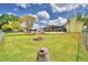 Wide shot of backyard with fire pit, patio, and yellow house against open yard with tree stump in foreground at 103 Lake Thomas Dr, Winter Haven, FL 33880
