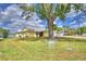 Charming home featuring a well-manicured lawn, mature tree, and serene lake views at 103 Lake Thomas Dr, Winter Haven, FL 33880
