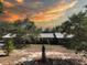 Charming single-story home featuring mature trees and a metal roof, set against a colorful sunset sky at 1432 Libby Rd, Babson Park, FL 33827