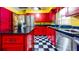This kitchen features black countertops, stainless steel appliances, checkered floors, and bright red cabinets at 1432 Libby Rd, Babson Park, FL 33827