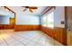 Spacious living room featuring wood-paneled walls, white tile flooring, and a large window showcasing the outdoor scenery at 1432 Libby Rd, Babson Park, FL 33827