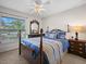 Bright bedroom features a four-poster bed, window with blinds, and a ceiling fan with lighting fixture at 1506 Chamberlain Loop, Lake Wales, FL 33853