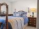 Bedroom boasts four-poster bed, decorative blue pillows, and nightstand with lamp and matching dresser at 1506 Chamberlain Loop, Lake Wales, FL 33853