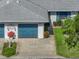 Charming home featuring a blue garage door, well-manicured lawn, and lush tropical landscaping at 1531 Oakview Se Cir, Winter Haven, FL 33880