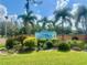 Community entrance with a sign amid lush tropical landscaping, and blue skies at 2055 S Floral Ave # 11, Bartow, FL 33830