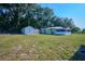 Expansive backyard featuring well-kept lawn, storage sheds, and mature trees provides a peaceful outdoor setting at 219 Willow St, Lake Wales, FL 33859