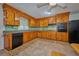 Kitchen featuring knotty wood cabinets, black appliances and tile flooring at 219 Willow St, Lake Wales, FL 33859