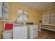 Functional laundry room with side-by-side washer and dryer, storage shelves, and bright yellow walls at 219 Willow St, Lake Wales, FL 33859