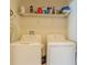 Laundry room features a GE washer and dryer with a wire shelf full of cleaning supplies above at 249 Haines Blvd, Winter Haven, FL 33881