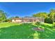 The backyard is large, with green grass, a pool enclosure, and landscaping at 2611 State Road 557, Lake Alfred, FL 33850