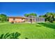 A fenced-in pool enclosure is featured in the rear of this home with green lawn at 2611 State Road 557, Lake Alfred, FL 33850