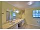 A bathroom with a double sink vanity, tile flooring, and framed mirror is nicely lit at 2611 State Road 557, Lake Alfred, FL 33850