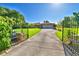 View of home through gated entrance, featuring a long driveway and mature trees at 2611 State Road 557, Lake Alfred, FL 33850