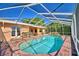 Screened in pool with brick decking is surrounded by potted plants and French doors to the home's interior at 2611 State Road 557, Lake Alfred, FL 33850