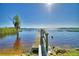Beautiful lake view from a wooden pier with bench seating, trees, and a blue sky on a bright, sunny day at 2611 State Road 557, Lake Alfred, FL 33850
