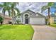 This charming single-story home boasts a well-manicured lawn, mature palm trees, and a two-car garage at 2721 Kokomo Loop, Haines City, FL 33844