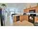 Open kitchen with light wood cabinets, black appliances, and tile flooring at 2721 Kokomo Loop, Haines City, FL 33844
