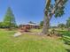 Expansive lawn with a wagon and vintage lawn equipment framing a single-story home with mature shade trees at 2726 Prine Rd, Lakeland, FL 33810