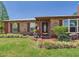 Inviting brick home with a manicured lawn, green hose, lush landscaping, and covered front porch at 2726 Prine Rd, Lakeland, FL 33810