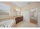 Bright bathroom featuring a soaking tub, wooden vanity, and large windows at 3565 Raleigh Dr, Winter Haven, FL 33884