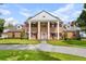 Stately brick home featuring large white columns, dormer windows, a manicured lawn and mature landscaping at 3826 Gaines Ct, Winter Haven, FL 33884