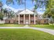 A sprawling brick home with white columns, black shutters, a lush green lawn, and mature trees at 3826 Gaines Ct, Winter Haven, FL 33884