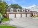 Four-car garage with brick exterior, dormer windows, and a concrete driveway at 3826 Gaines Ct, Winter Haven, FL 33884