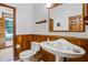 Unique bathroom showcasing wood paneling, modern toilet, and pedestal sink with a matching mirror at 553 Thornburg Rd, Babson Park, FL 33827