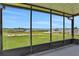 Enclosed patio area overlooking the lake, grassy shore, and two wooden docks in the distance at 553 Thornburg Rd, Babson Park, FL 33827