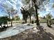 Backyard with a concrete patio and mature trees, partially enclosed by a white fence at 605 Wanamaker Ave, Fort Meade, FL 33841