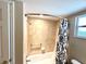 Bathroom shower featuring tan tiled walls, shower head, grab bar, and black and white patterned curtain at 605 Wanamaker Ave, Fort Meade, FL 33841
